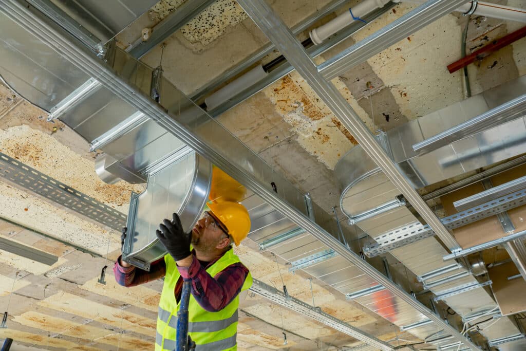 Manual worker installing air conditioner in building.