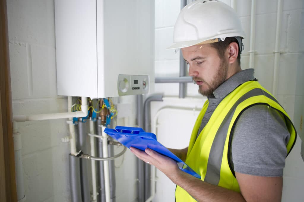 Plumbing contractor examines boiler